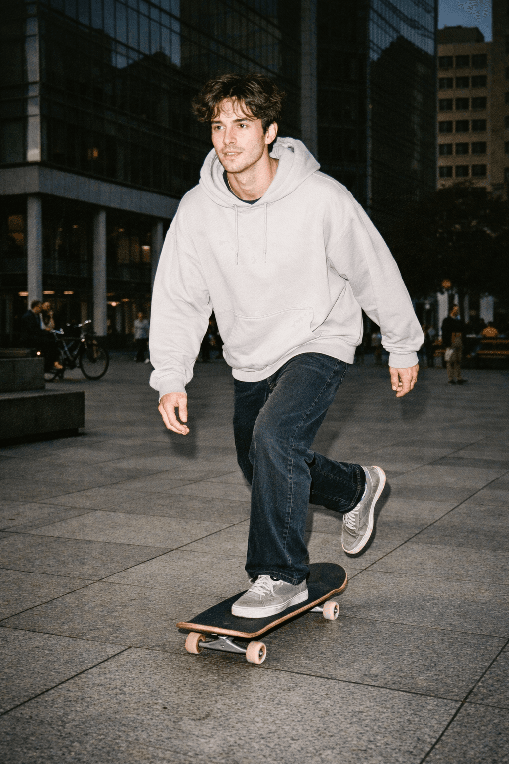Young man skateboarding through a city plaza, captured mid-push, lit by a harsh disposable-camera flash that brightens him while the background falls into darker shadows.